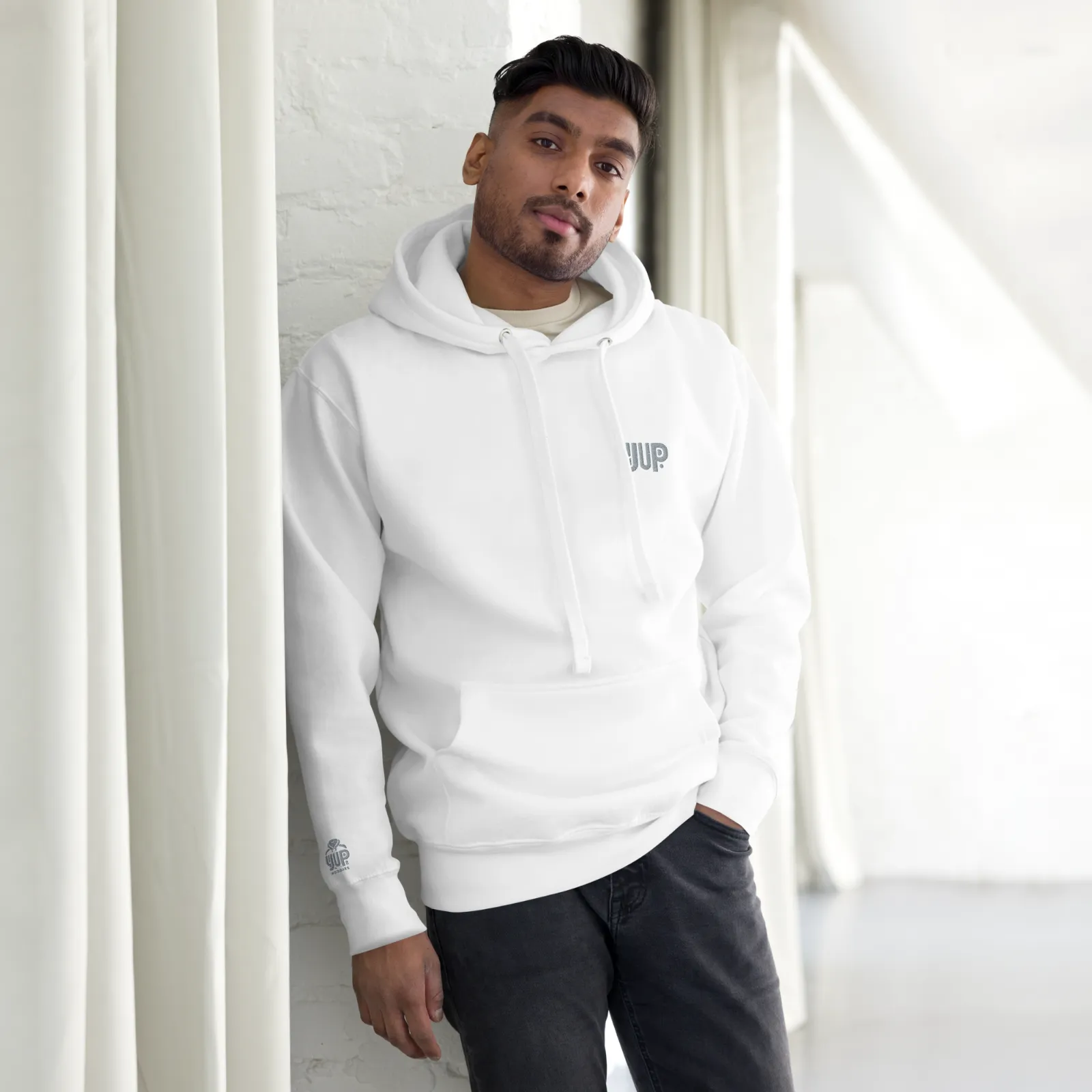 Model wearing a white YUP Hoodie in a sunlit space